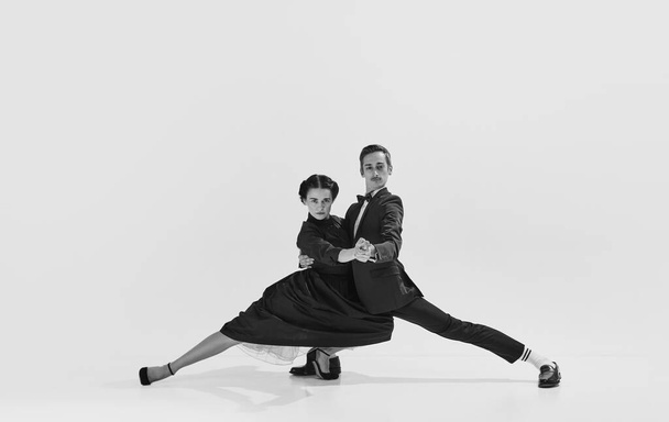 Talented and artistic young man in suit and beautiful woman in elegant dress dancing lindy hop. Black and white. Concept of hobby, retro dance, vintage style, choreography, beauty. Monochrome art. Ad - Photo, Image
