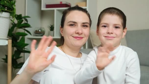 Een jonge moeder en een zesjarige zoon zwaaien met hun handen in groeten naar de camera kijkend. Gelukkig moederschap, Moederdag - Video