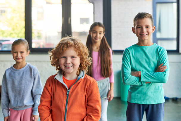 четыре весёлых ребенка-подростка позируют в спортзале и радостно улыбаются перед камерой, детским спортом - Фото, изображение