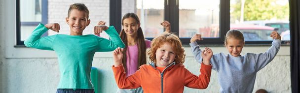 four cute little children in sportswear playing muscles and smiling at camera, child sport, banner - Photo, Image
