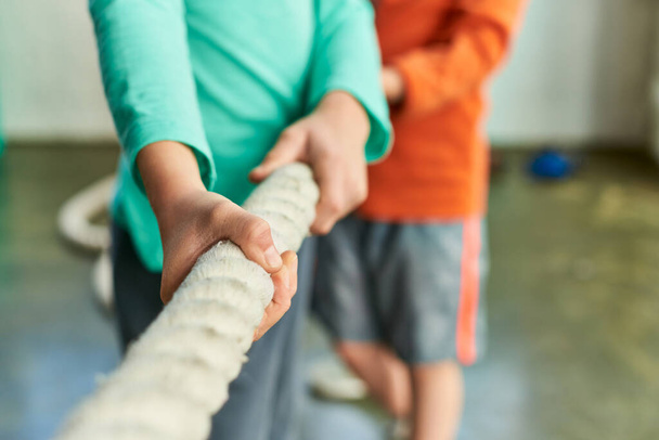 cropped view of two children in sportswear pulling fitness rope in gym, child sport - Photo, Image
