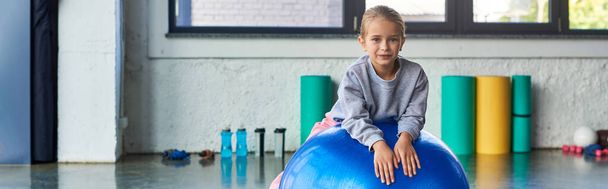 aranyos kislány -ban sportruházat fekvő fitness labda és mosolygós a kamera, gyermek sport, banner - Fotó, kép