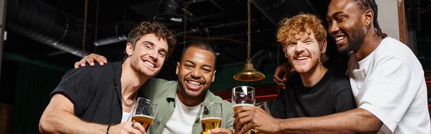 gelukkig interraciale mannen toosten met een bril van bier in bar tijdens vrijgezellenfeest, vriendschap banner - Foto, afbeelding