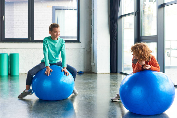 two preadolescent cute boys in sportswear exercising actively on fitness balls, child sport - Photo, Image