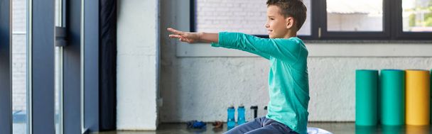 schattig vooradolescent jongen in blauw sportkleding poseren in profiel en lichaamsbeweging, kindersport, banner - Foto, afbeelding