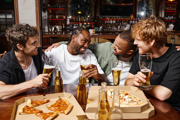 group of happy multicultural male friends chatting and holding glasses of beer, spending time in bar - Photo, Image