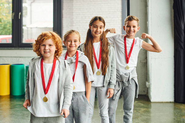 radostné děti ve sportovním oblečení se zlatými medailemi vesele se usmívající na kameru, dětský sport - Fotografie, Obrázek