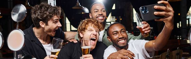 幸せな異人種間の男性のバナー スマートフォンでセルフィーを取るとバーでビールを保持, 独身パーティー - 写真・画像