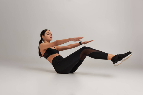 fiatal sportos nő fekete aktív kopás fitness nyomkövető csuklón edz szürke háttér - Fotó, kép