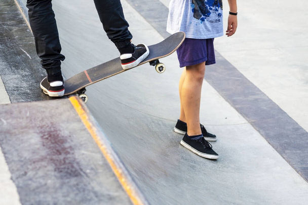 The skateboarder before descent from the hill. The guy shows to the friend how to go down on a board. Concept of Healthy lifestyle. Sports hobby.The guy on a skateboard.  Sports hobby. Skateboard active urban life style.  man in a sports helmet on th - Foto, Imagem