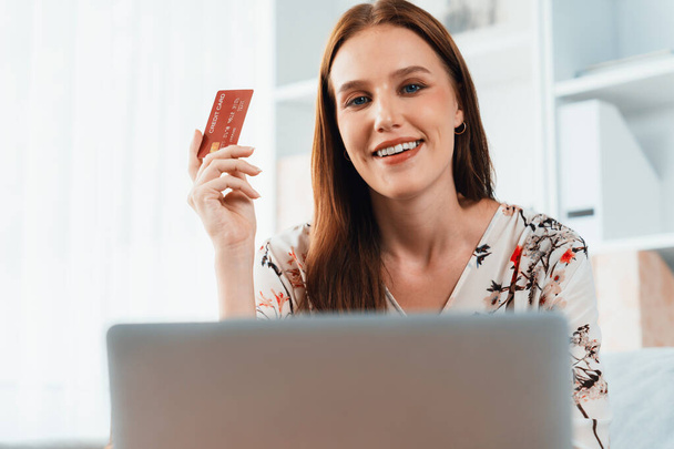 Young happy woman buy product by online shopping at home while ordering items from the internet with credit card online payment system protected by utmost cyber security from online store platform - Photo, Image