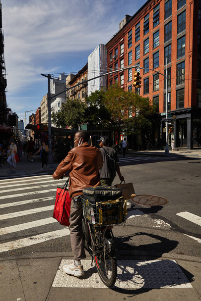 NEW YORK, USA - NOVEMBER 26, 2022: african american cyclist waiting on crossroad with traffic lights - 写真・画像