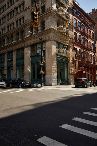 ニューヨーク市のダウンタウン通りのクロスロード上の消火脱出階段と車が付いている角の建物 - 写真・画像