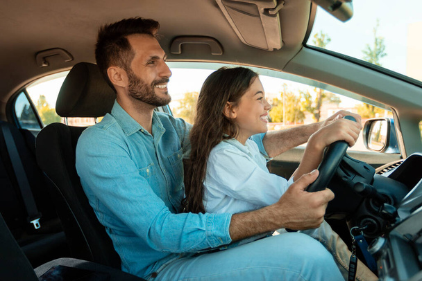 Mutlu genç baba ve genç kız birlikte araba sürüyorlar, çocuk babasıyla oturuyor, direksiyonda el ele tutuşuyorlar. Babalık, ebeveynlik, aile, şefkat - Fotoğraf, Görsel