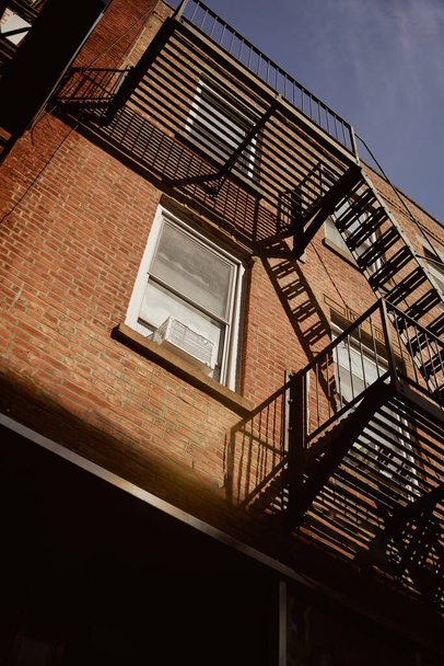 baixo ângulo vista do edifício de tijolos com escadas de escada de incêndio na cidade de Nova Iorque, arquitetura urbana - Foto, Imagem