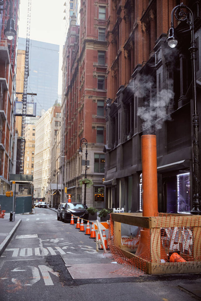 tubo di ventilazione fumante vicino alle auto sulla carreggiata stretta nella città di New York, atmosfera metropoli - Foto, immagini