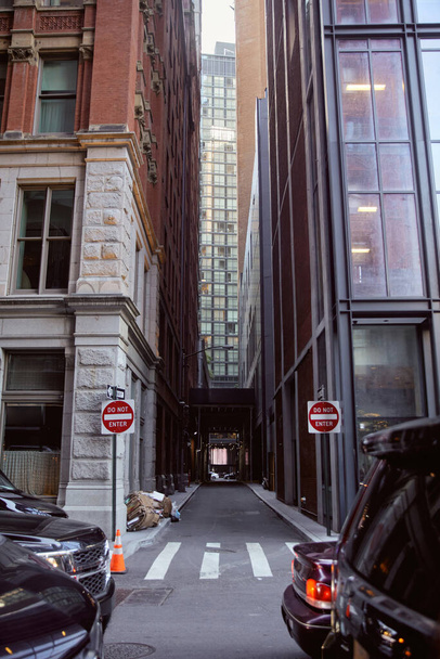 Autos, die in der Nähe geparkt werden, fahren nicht in Straßenschilder zwischen modernen Gebäuden an der Stadtstraße in New York City - Foto, Bild