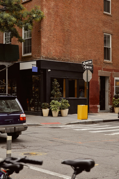 brick building with storefront and flowerpots near crossroad in new york city downtown, streetscape - Photo, Image