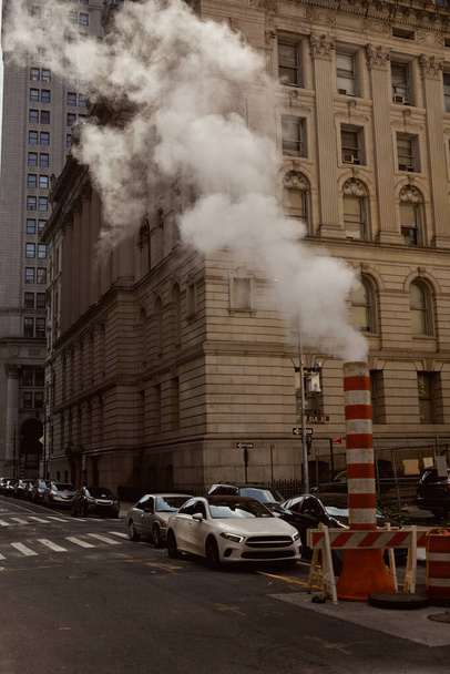 улица Нью-Йорка с транспортными средствами, движущимися по проезжей части рядом с паровой трубой, городская атмосфера - Фото, изображение