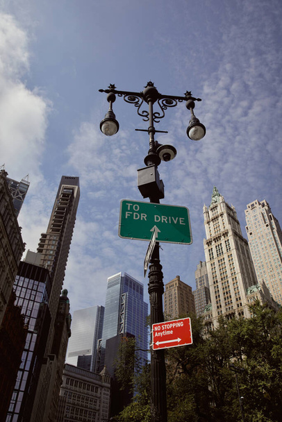 nízký úhel pohledu na pouliční sloup s lucernami a dopravní značky proti mrakodrapům v New Yorku - Fotografie, Obrázek