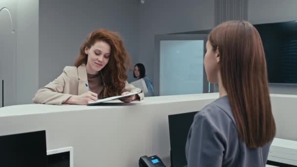 Jovem paciente do sexo feminino assina documento de acordo na recepção do hospital moderno - Filmagem, Vídeo