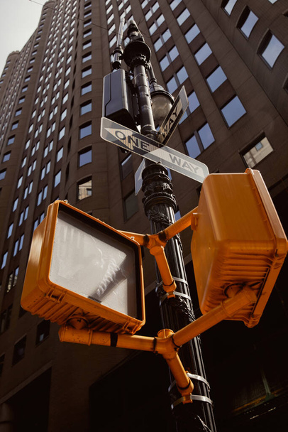 Straßenmast mit Ampeln und Verkehrsschildern in der Nähe moderner Gebäude in New York City, niedriger Blickwinkel - Foto, Bild