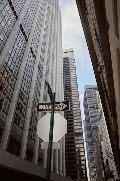 New York 'taki modern binaların ve gökdelenlerin yakınındaki tek yönlü yol tabelasının alçak açılı görüntüsü - Fotoğraf, Görsel