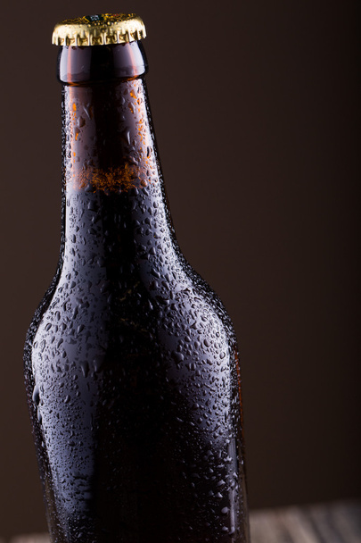 Bottiglia di birra con gocce d'acqua su sfondo dorato
. - Foto, immagini