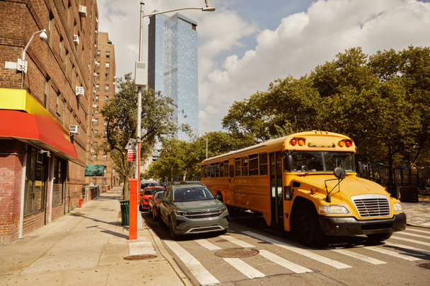 żółty autobus szkolny i samochody na przejściu obok drzew z jesiennymi liśćmi w Nowym Jorku, scena jesienna - Zdjęcie, obraz