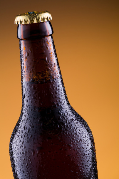 Μπουκάλι μπύρας σε χρυσό υπόβαθρο. - Φωτογραφία, εικόνα