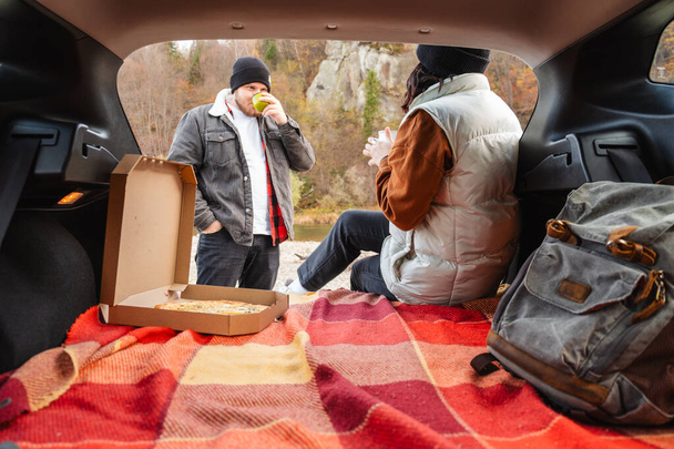 couple sitting in car trunk having picnic resting at nature autumn season - Photo, Image