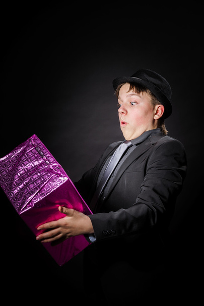 Expressive teenage boy holding box with gift - Foto, Imagem