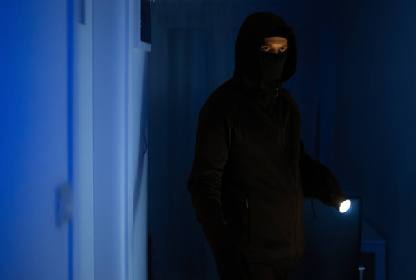 Ladrón enmascarado con linterna de control de la antorcha apartamento. - Foto, imagen