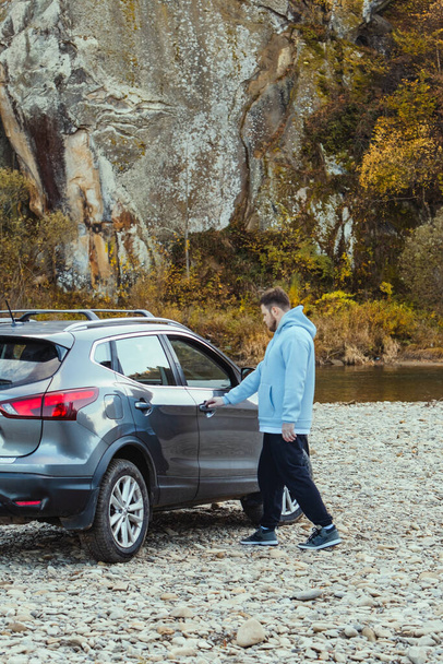 man car traveler stop at river rocky beach enjoying the autumn forest copy space - Photo, Image