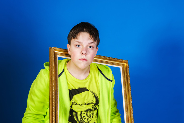 Affective teenage boy posing with picture frame - Foto, Imagen