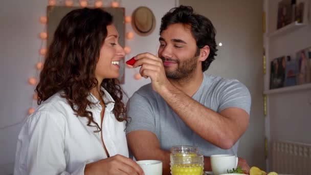 Νεαρό ζευγάρι τρώει πρωινό, παίζει ρομαντικά και γελάει  - Πλάνα, βίντεο