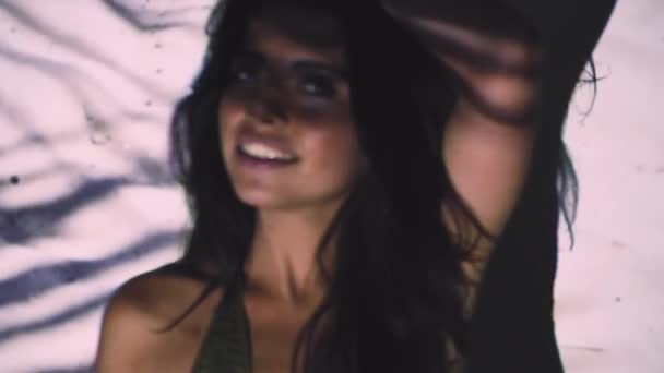 портретне зображення красивої молодої жінки, що позує в купальнику під проекцією з тропічним листям - Кадри, відео