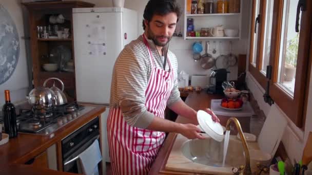 台所の若い男が皿を洗っている - 映像、動画