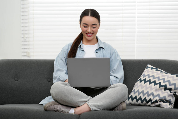 Woman using laptop on couch at home - Foto, imagen
