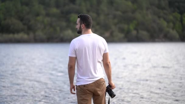 νεαρός άνδρας με κάμερα στη λίμνη - Πλάνα, βίντεο