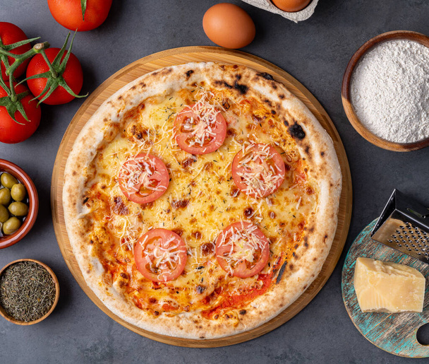 Napolitan pizza with tomatoes, olive oil, eggs and flour over wooden table. - Photo, Image