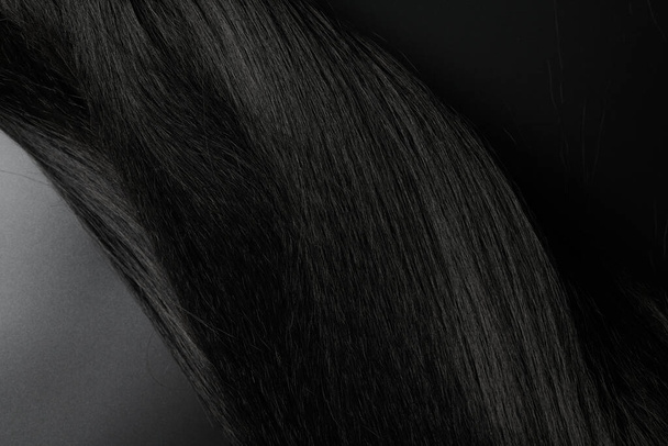 Close-up view of natural shiny dark hair, bunch of black brunette curls background - Zdjęcie, obraz