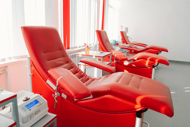 Sillones rojos para sentarse en el centro de donación. Estación de transfusión de sangre para extraer sangre de donantes - Foto, Imagen