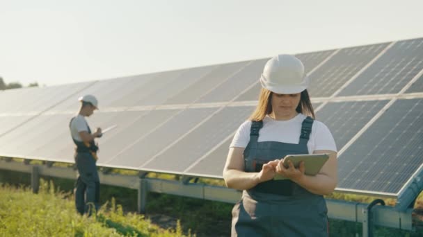 Жінка-інженер використовує планшет для збору ефективної інформації про сонячні панелі. Фотоелектрична сонячна ферма. Зелена енергія. Середа. Концепція зеленої енергії. Високоякісні 4k кадри - Кадри, відео