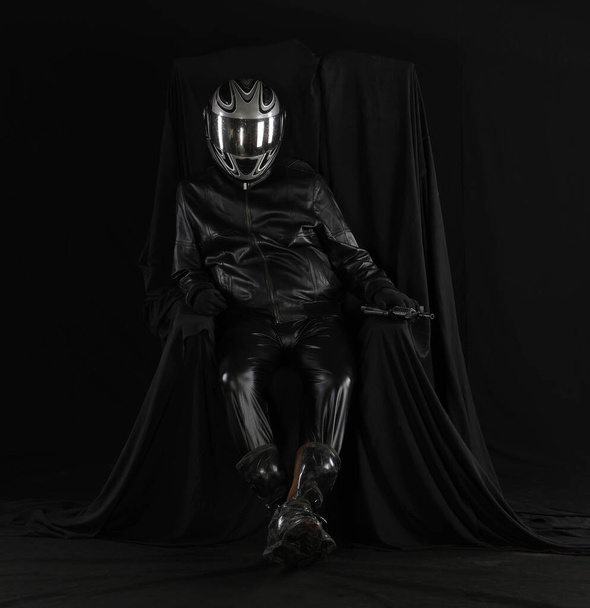 黒い背景の椅子のヘルメットのバイカーの肖像画 - 写真・画像