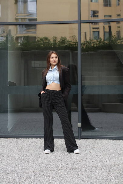 Portrait shooting of a stylish girl. Dark shades. Trends of spring and summer 2023. Business lady. Classic jacket and black pants. Blue shirt. Business center. Office work - Φωτογραφία, εικόνα