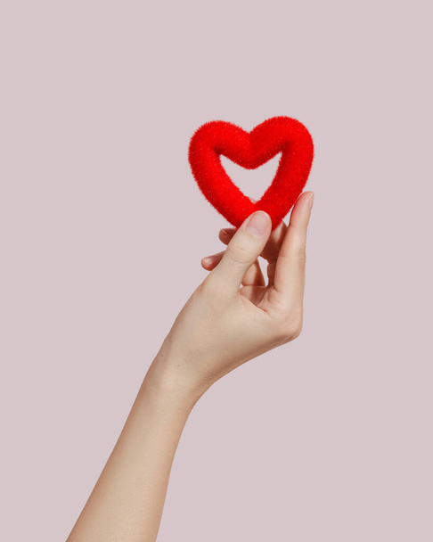 Rotes weiches Herz in jungen Frauenhänden auf rosa Hintergrund. Liebe und Glück Konzept. Spendenkonzepte - Foto, Bild