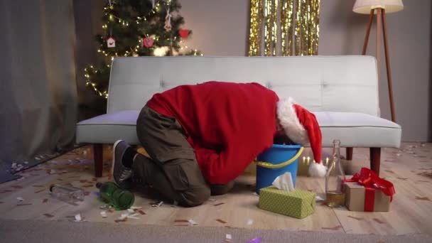 Homme millénaire en chapeau de Père Noël souffrant de nausées et gueule de bois après la fête de Noël. Concept d'intoxication et de dépendance à l'alcool - Séquence, vidéo