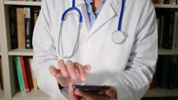 Lähikuva naislääkäri pukeutuu valkoiseen takkiin sairaalassa ja älypuhelimella - Materiaali, video