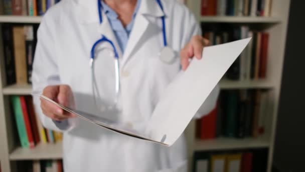 Close-up kobieta lekarz nosi biały płaszcz stoi w szpitalu i posiada folder z dokumentami dokumenty, diagnozy, recepty - Materiał filmowy, wideo